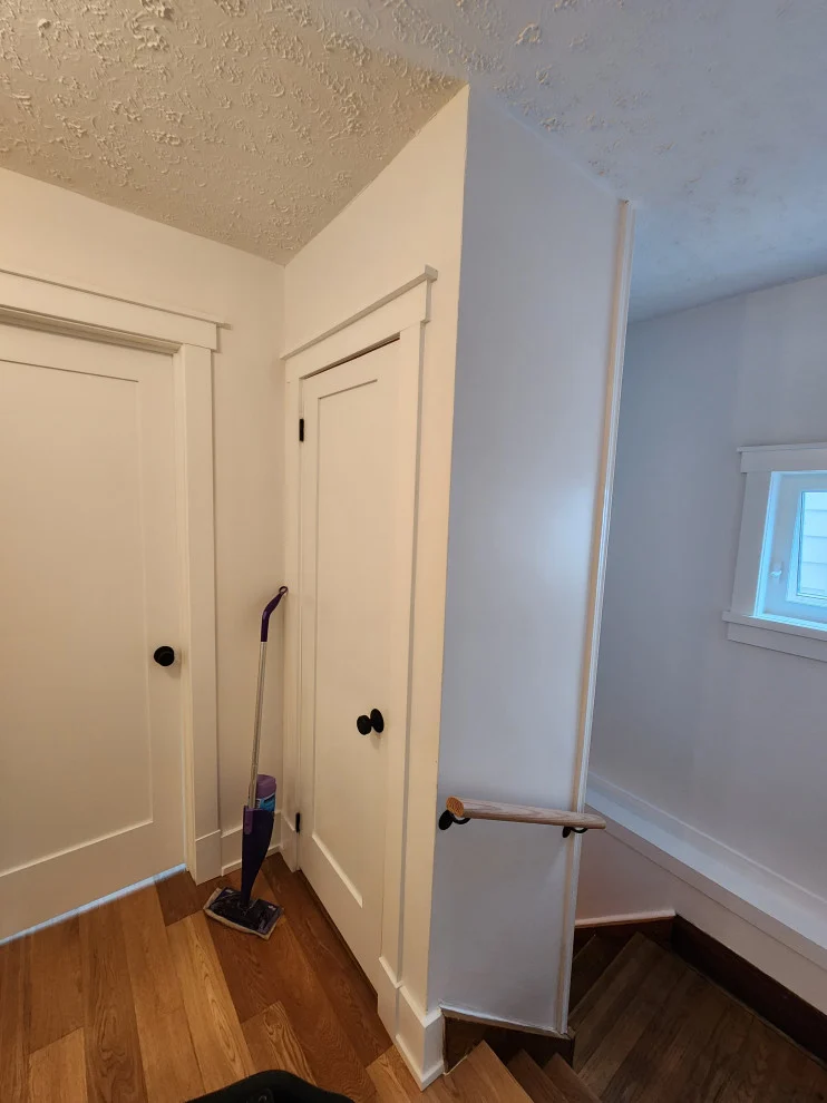 Upstairs landing with new hardwood floor, white shaker doors and stair handrail