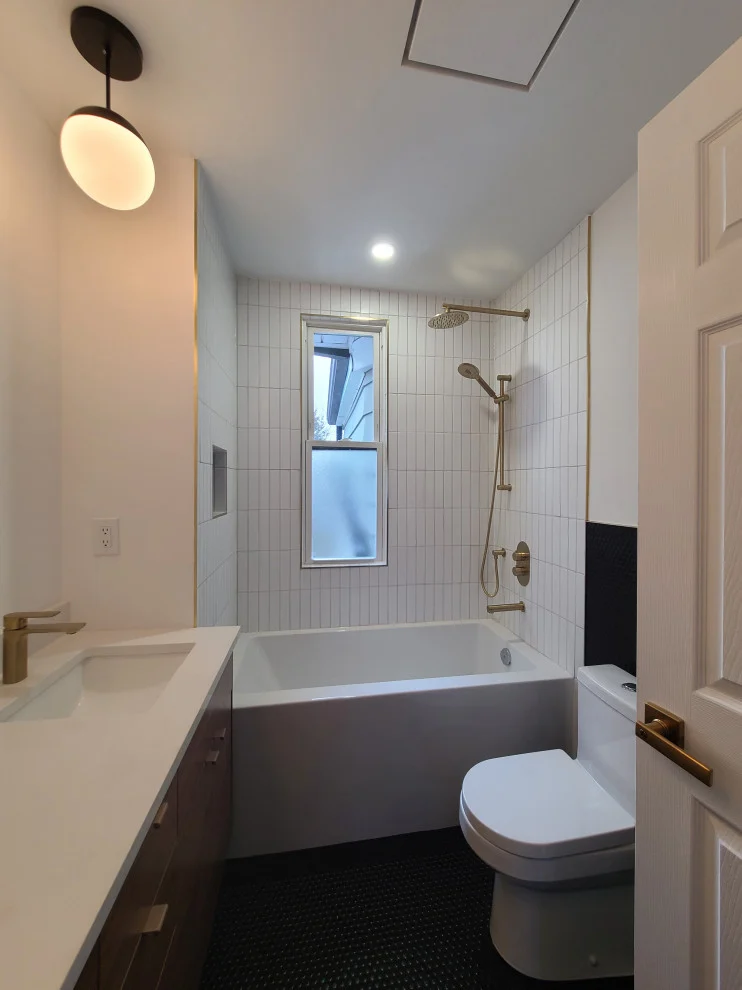 Bathroom with long white vanity, alcove tub, white vertical tile and gold shower fixtures
