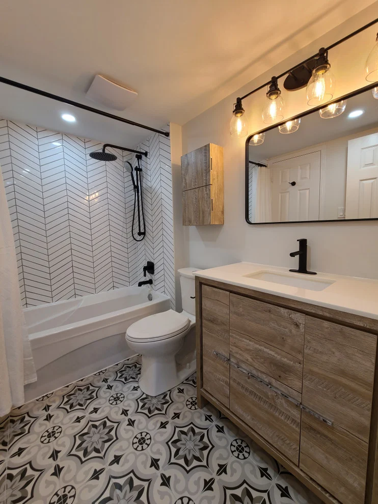 Bathroom with white chevron tub surround, wood-look vanity, black fixtures and patterned grey floor tile