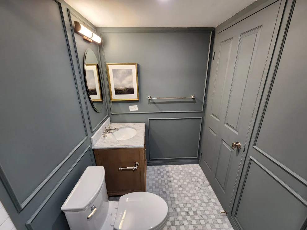 Bathroom with grey picture frame wall moulding, wood vanity, framed art and marble mosaic floor