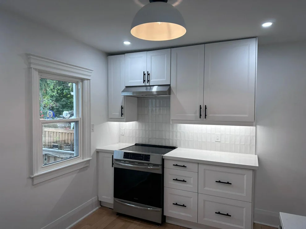 White shaker cabinets with stainless range, range hood, under-cabinet lights and dome pendant