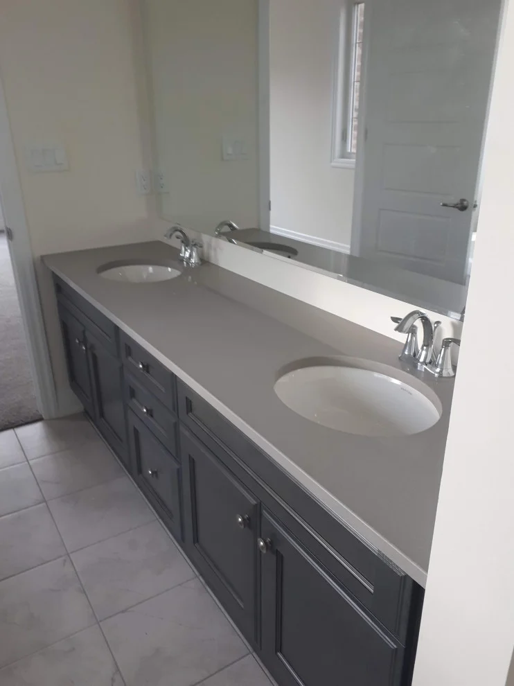 Long double vanity with dark grey shaker cabinets, grey countertop and two undermount sinks