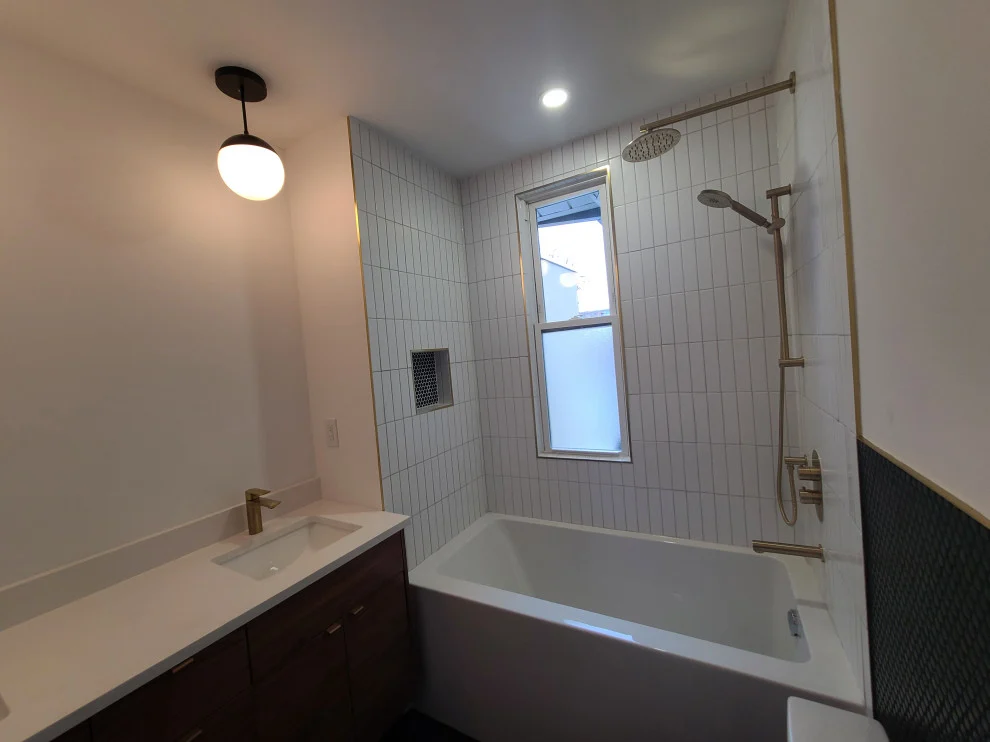 Tub alcove with white vertical stacked tile, window, gold shower set and globe pendant light