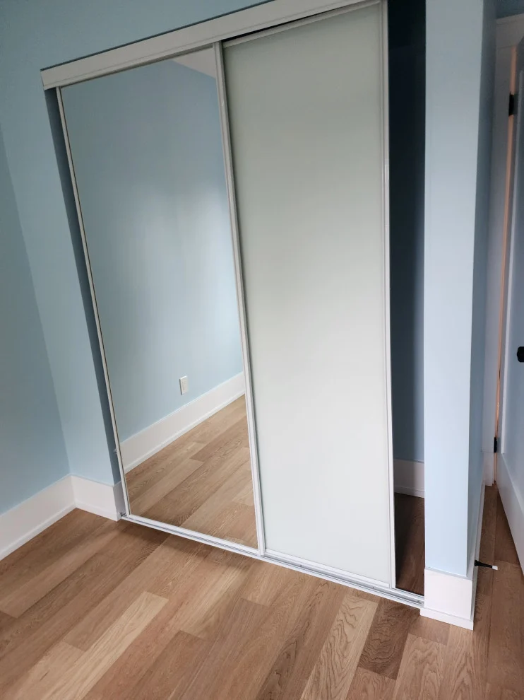 Mirrored sliding closet doors in pale blue room with light oak hardwood flooring