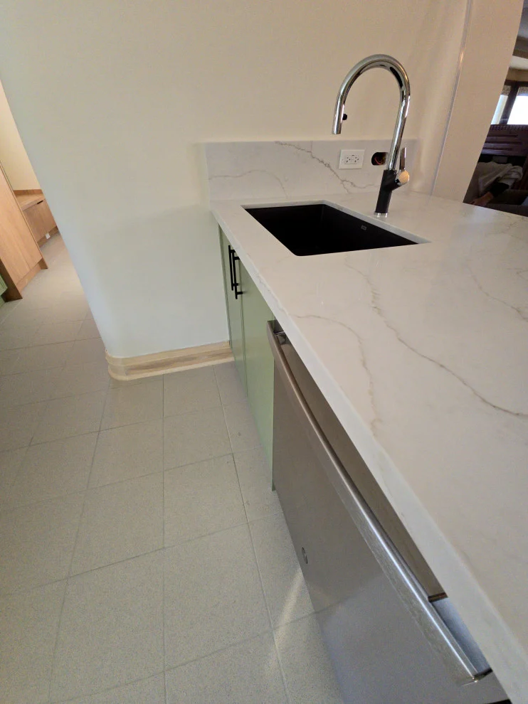 White veined quartz counter with black undermount sink, chrome faucet and stainless dishwasher