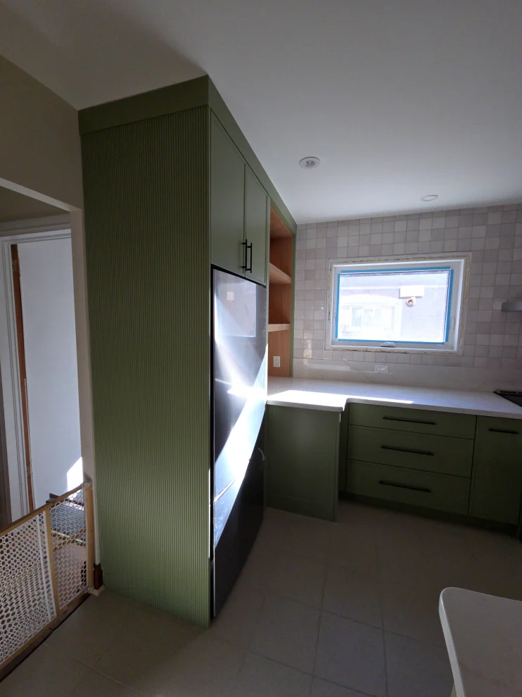Tall green pantry cabinet and fridge wall leading to corner counter and window