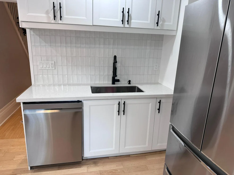 Sink wall with white shaker cabinets beside a stainless French door fridge