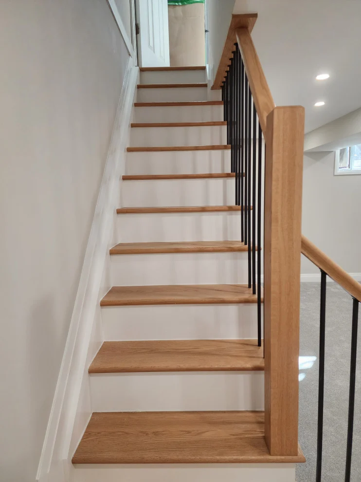Looking up oak stair treads with white risers and oak handrail with black spindles