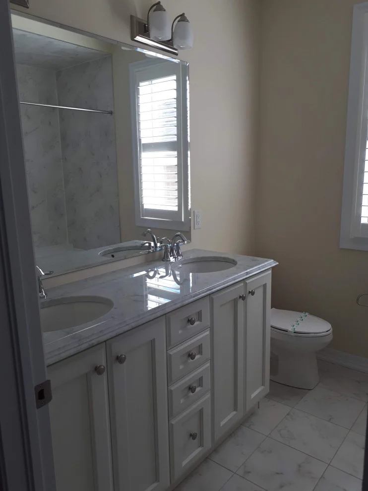White shaker double vanity with grey countertop, large mirror and marble-look floor tile