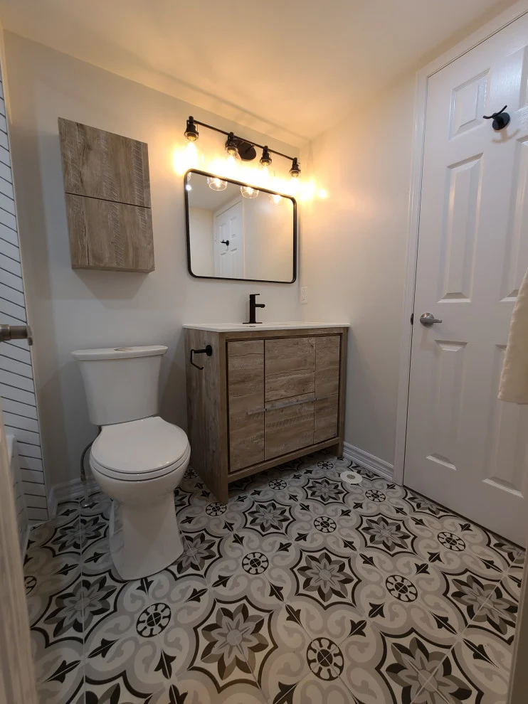 Toilet beside wood-look vanity with black faucet, black mirror and four globe vanity light