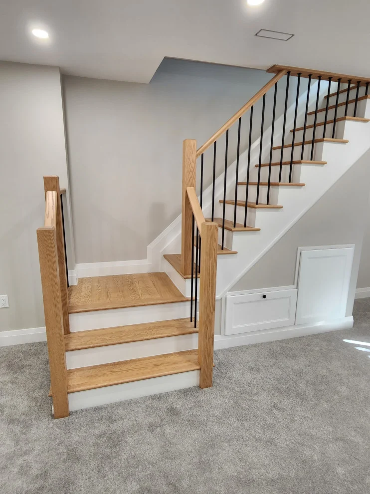 Oak and white staircase with black spindles, under-stair access panel and grey carpet