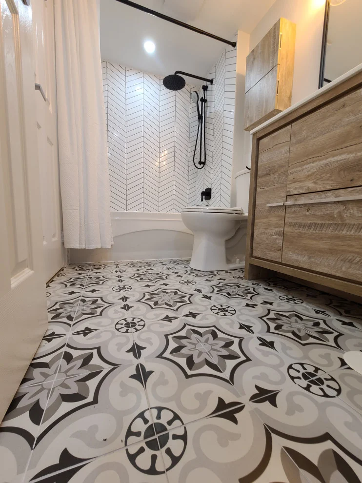 Grey and white patterned encaustic-look floor tile beside wood-look vanity and tub