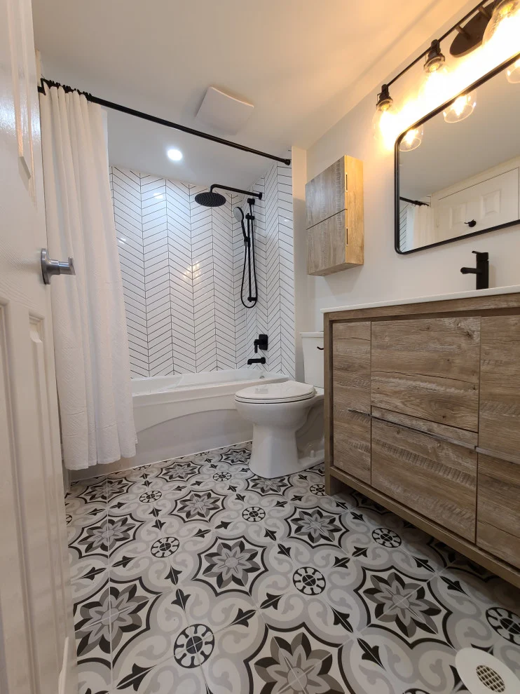Tub with shower curtain, chevron tile surround and long wood-look vanity on patterned floor