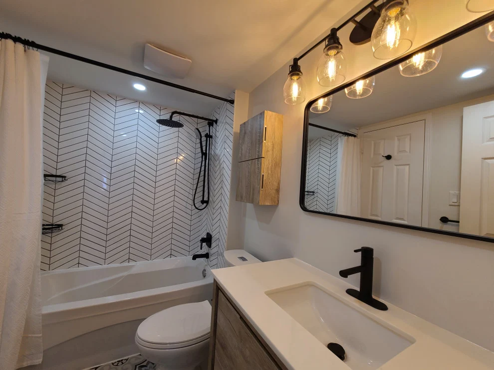White chevron tub surround, black rain shower, undermount sink and black framed mirror with globe lights