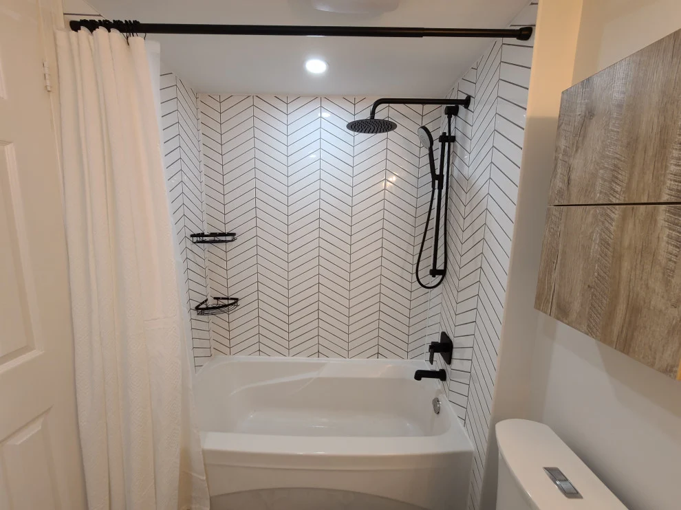 Bathtub with white chevron tile surround, matte black shower set and white shower curtain